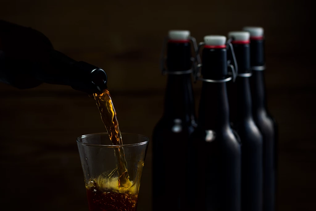 Bière servie dans un verre adapté avec bouteilles en fond
