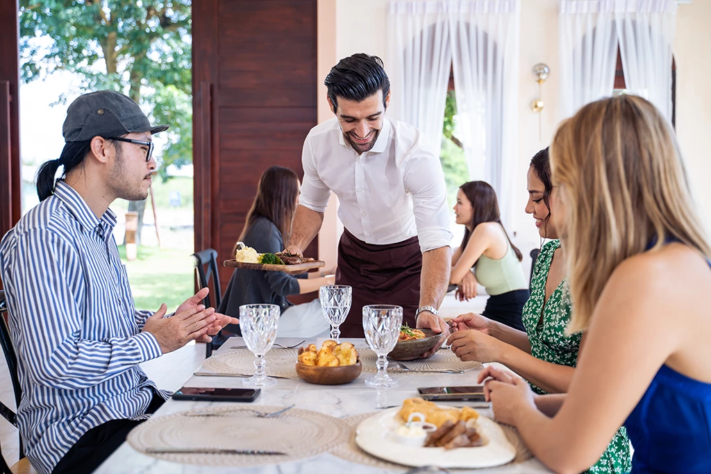 Serveur amenant le repas à une table en restaurant