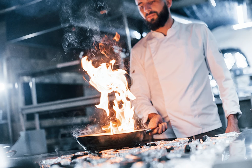 Chef en uniforme en train de faire frire sa nourriture