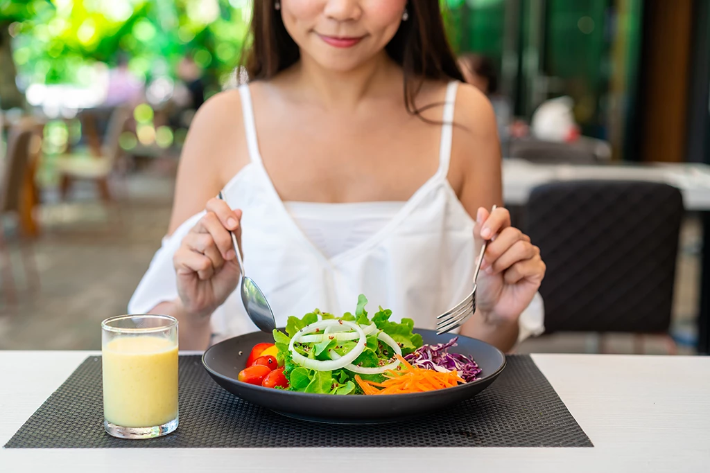 Jeune femme mangeant sainement une salade au restaurant